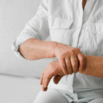 Wanita paruh baya memegang pergelangan tangan karena nyeri sendi asam urat.