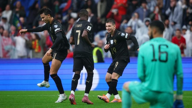Tiga pemain timnas Jerman (termasuk Jonas Hofmann #11 dan Julian Brandt #19) merayakan gol dengan seragam hitam di lapangan hijau.