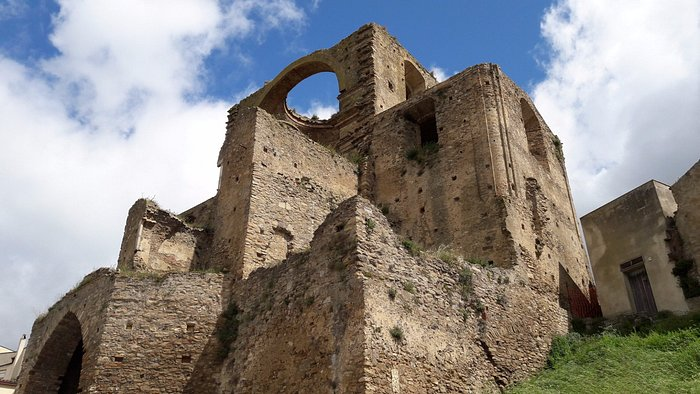 Gang sempit di desa Italia dengan bangunan batu tua dan tanaman hias.