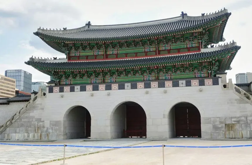 Struktur megah Gerbang Gwanghwamun di siang hari dengan langit sedikit berawan.